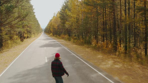 Young happy man is riding on longboard Autumn road Eastern Sayan Siberia Buryatia Arshan