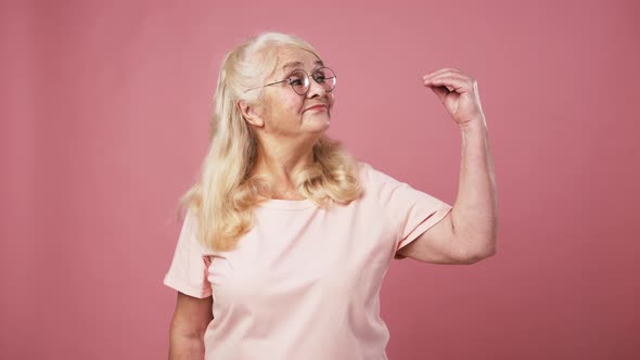Skeptical Elderly Woman Showing Bla Bla Gesture with Her Hand Expressing Mistrust and Disbelief Pink