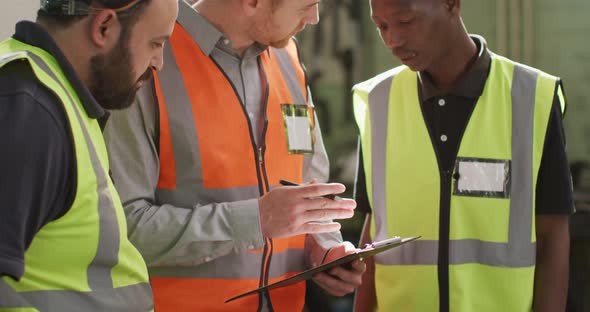 Two Caucasian and an African American male factory worker at a factory in discussion