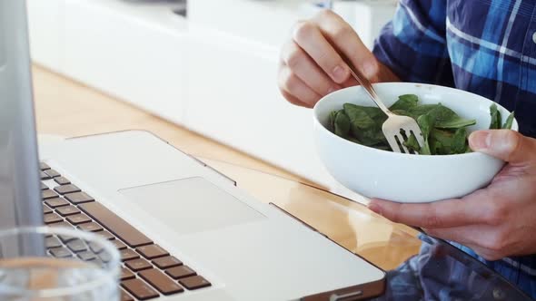 Man having breakfast while using laptop at home 4k