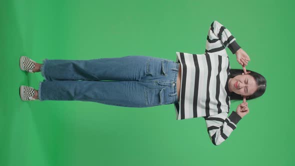 Full Body Of Stressed Asian Woman Covering Her Ears While Standing In Front Of Green Screen