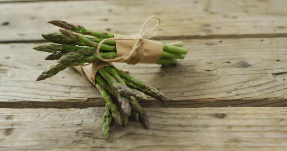 Video of two fresh asparagus bundles on wooden background