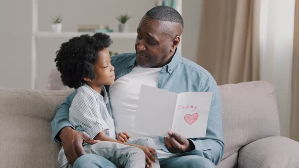 Happy Man Sitting on Couch Hugging Beloved Daughter Reading Postcard Cute Kid Girl Wishes Dad Happy