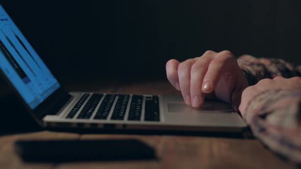 Hands of a man working on laptop at night.