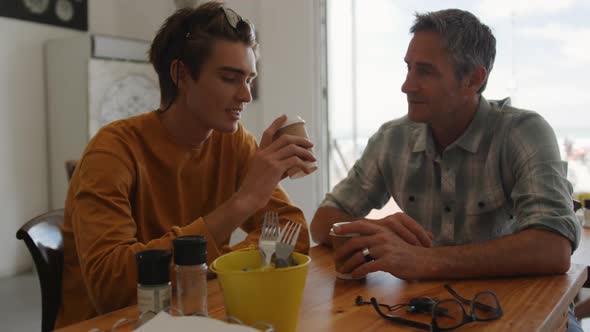 Father and young adult son in a cafe together