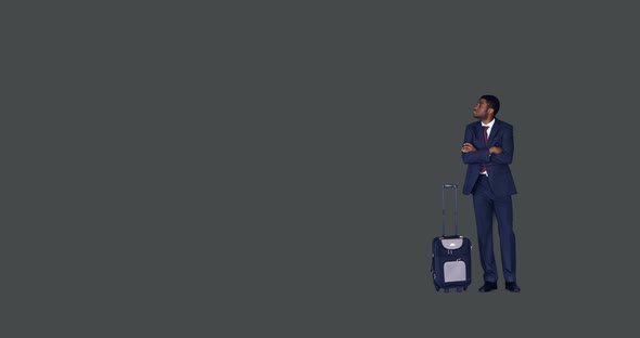 Businessman standing with arms crossed with his luggage