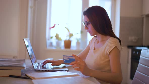Young Woman Pays for Credit Card Shopping Uses Laptop and Enjoys It Very Much