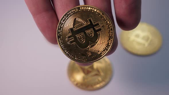 Man Hand Holds a Gold Coin Bitcoin Which He Has Mined for Himself on Crypto Farm