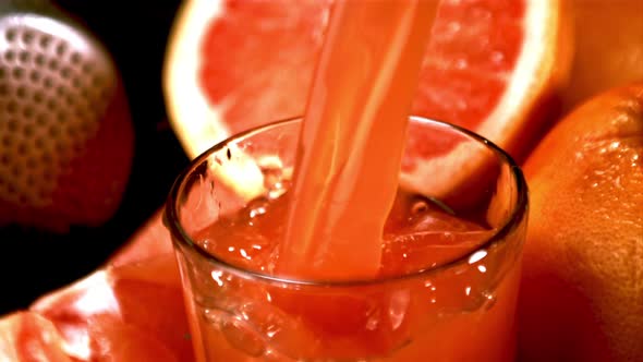 Super Slow Motion Grapefruit Juice Pours Into the Glass Over the Edge