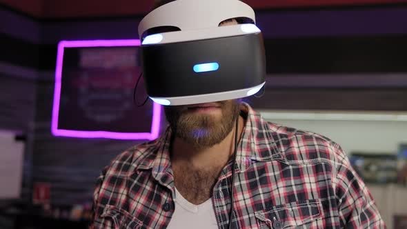 Portrait of a Young Bearded Man Wearing Virtual Reality Glasses in a Game Room