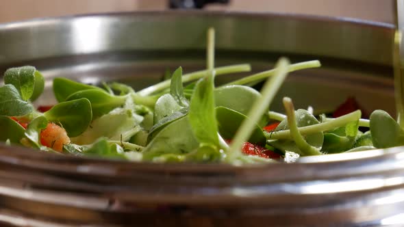 Pouring extra virgin olive oil on freshly chopped salad in close up view