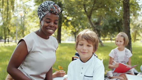 Joyous Multiethnic Teacher and Boy Posing for Camera during Outdoor Lesson