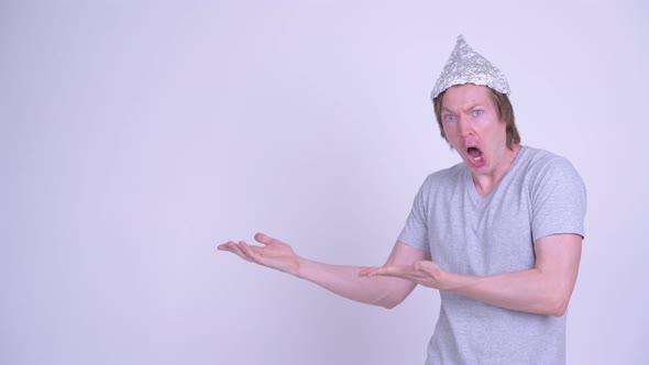 Young Man with Tinfoil Hat Showing Something and Looking Shocked