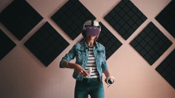 Beautiful Girl in a Virtual Reality Helmet with Controllers in Hands