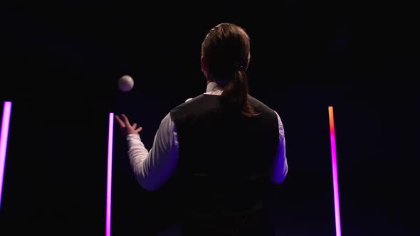 Orbital Shot Professional Circus Performer Juggling with Five White Balls Against a Black Studio