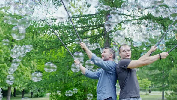 Men Performing Soap Bubbles Tricks in Park