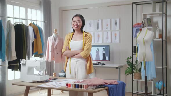 Female Designer With Measuring Tape Around Her Neck Smiling And Crossing Her Arms To The Camera