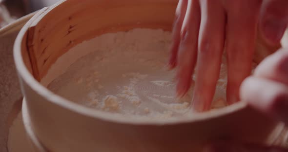 Woman Sifts Flour Through Sieve in the Kitchen While Baking Croissants