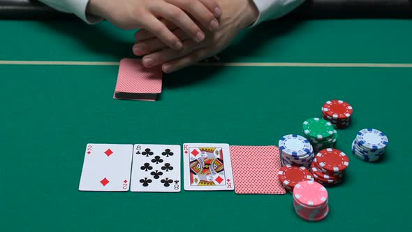 Male Croupier Dealt Cards and Waiting Players Making Bets, Poker Game in Casino