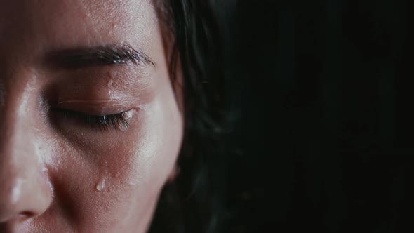 Half Portrait of a Woman with Closed Eyes Under Rain on Dark Background