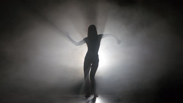 Leggy Girl Dancing in a Smoky Studio Rhythmic Dance. Silhouette