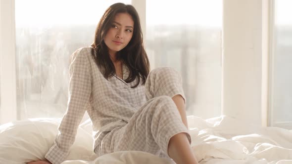 Asian Woman Sitting on a Bed at Home