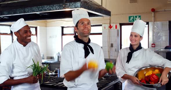 Head chef juggling vegetables and colleagues watching