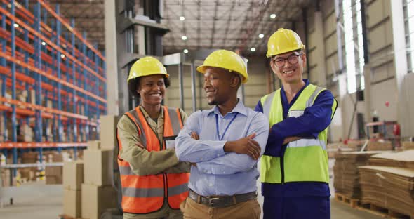 Portrait of diverse workers wearing safety suits and smiling in warehouse