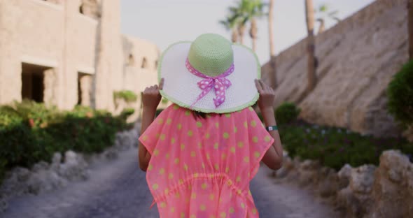 Back View of Young Girl in Hat Walking on Alley at Tropical Resort