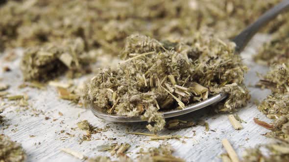 Dried crushed medicinal herb in a metal spoon close up on a wooden table