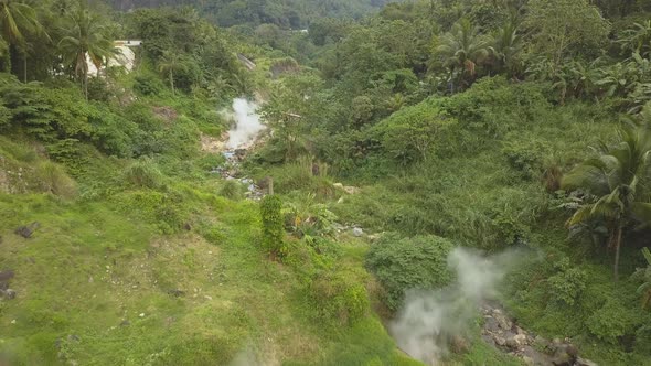 Aerial View Steam Comes Out of the Ground in a Green Forest Around a Mountain and a River