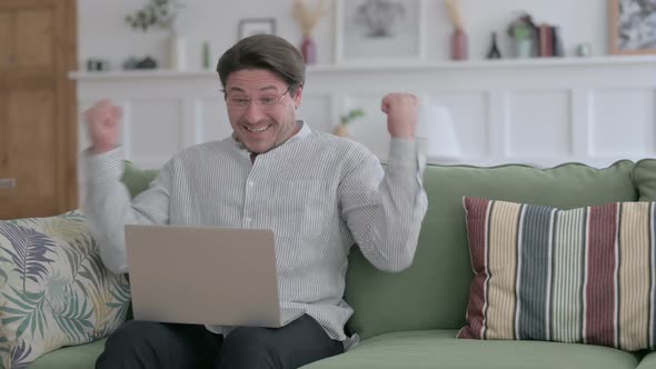 Man with Laptop Celebrating Success on Sofa