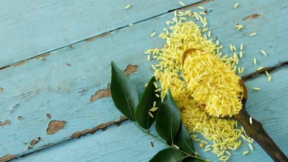 Raw organic yellow rice and curry leaves on wooden table 4k