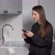 A Young Woman in the Kitchen Uses a Mobile Phone - VideoHive Item for Sale