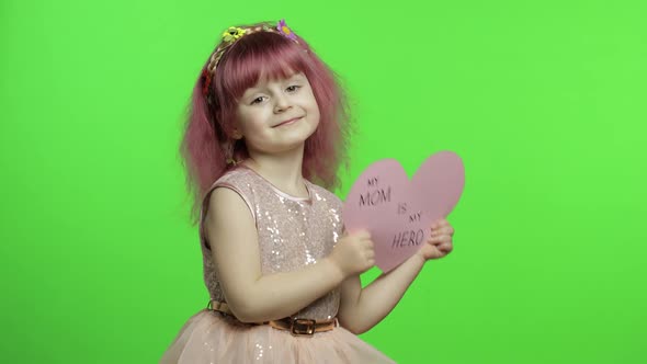 Child Girl Princess Holds Pink Paper Heart with Text About Mother. Mother's Day