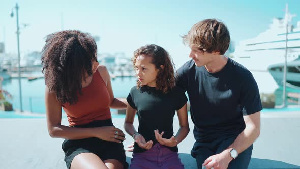 Laughing multiethnic family talking with displeased daughter on the embankment