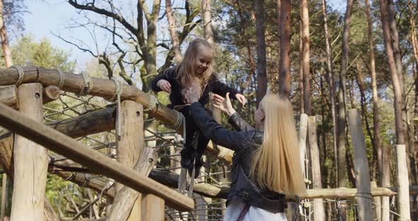 Little Girl Jumps On Mom's Arms In The Recreation Park
