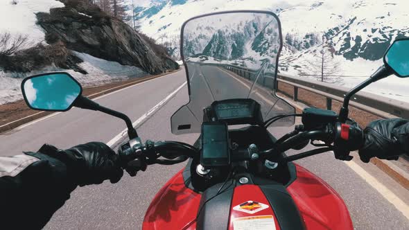 Motorcyclist Rides on a Beautiful Landscape Snowy Mountain Road Near Swiss Alps. Switzerland.