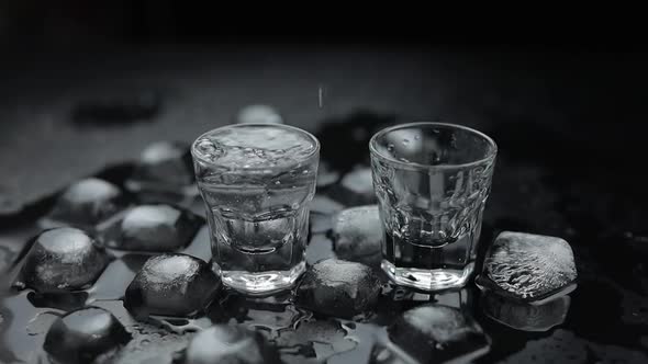 Pouring Up Shots of Vodka From a Bottle Into Glass. Black Background