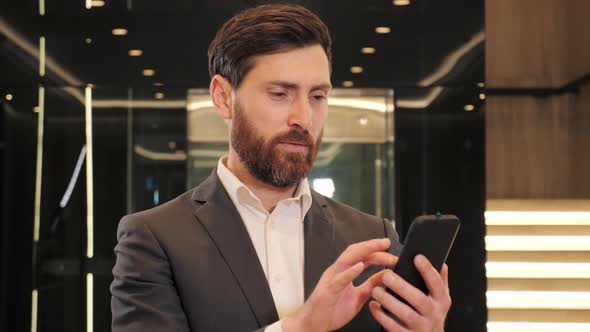 Businessman Reading Good News on Mobile Phone Indoor