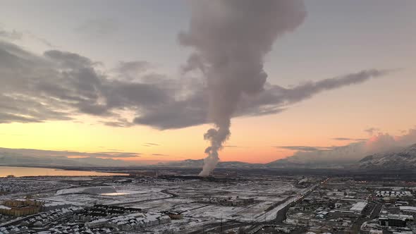 Aerial winter sunset view flying backwards viewing smoke from factory