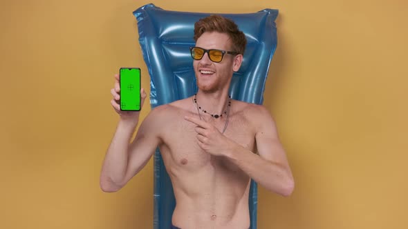 Redhaired Man Lies on an Inflatable Mattress Shows on a Blank Screen of the Phone