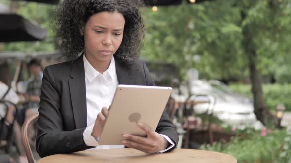 African Woman Using Tablet Sitting in Outdoor Cafe