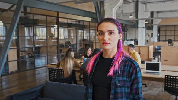 Portrait of Informal Woman with Pink Hair Posing at Office Looking at Camera Tracking Shot