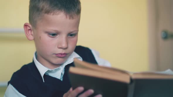 Upset Boy Turns Pages of Textbook Preparing for Test at Home