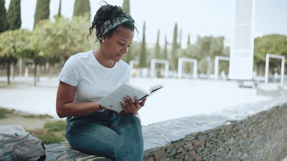 Pleased brunette African woman reading book