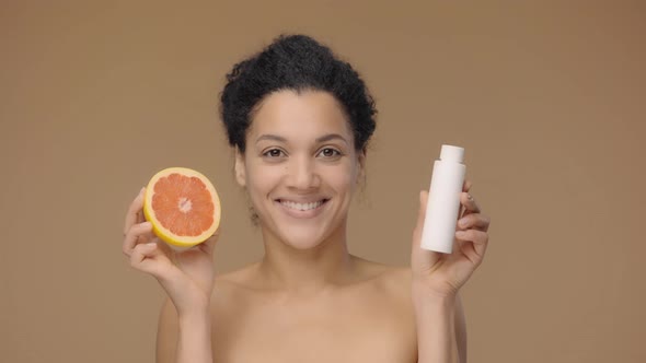 Beauty Portrait Young African American Woman Holding Half Grapefruit and Facial Lotion Making Choice