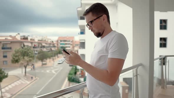 Man with Smartphone on Balcony.