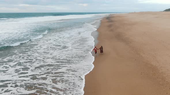 Loving Couple Running Along the Beach By the Ocean Holding Hands