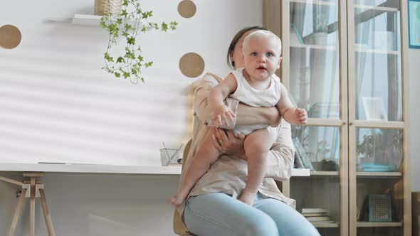 Woman Holding Baby while Sitting on Office Chair